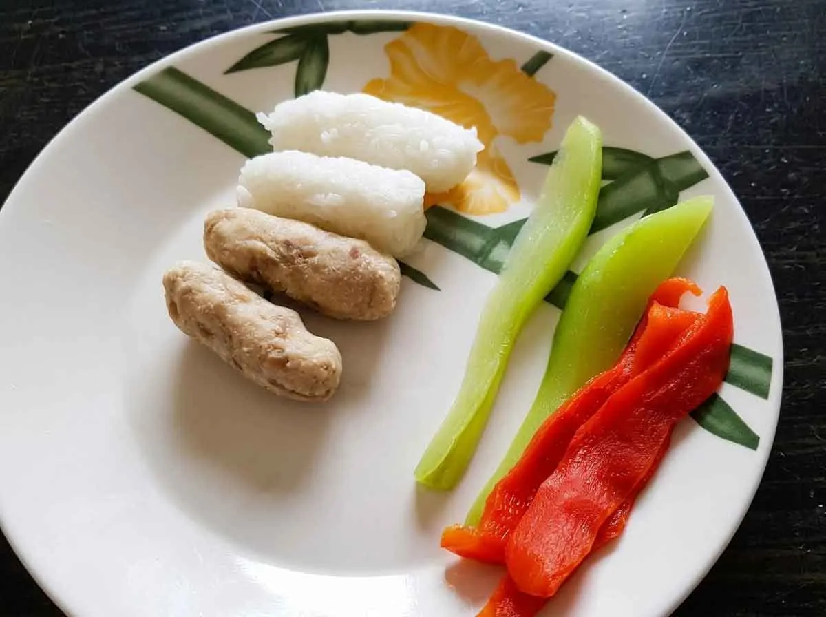 Prato de bebê de 7 meses com bolinhos de arroz, bolinhos de proteína, chuchu e pimentão em tiras