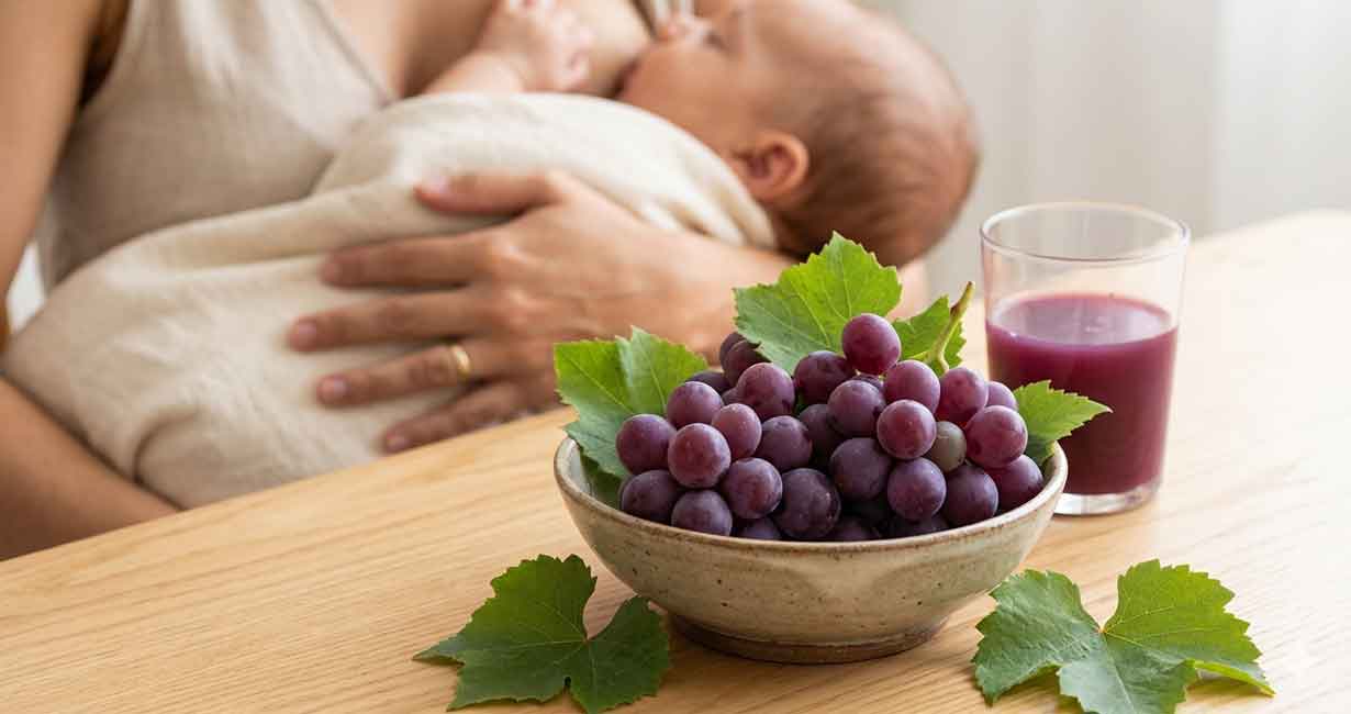 Cacho de uvas roxas frescas em uma mesa de madeira, com mãe amamentando bebê ao fundo - Nutrição Materno-Infantil Thayssa Roriz